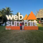 Placa do WebSummit com duas mulheres em pé na frente da placa