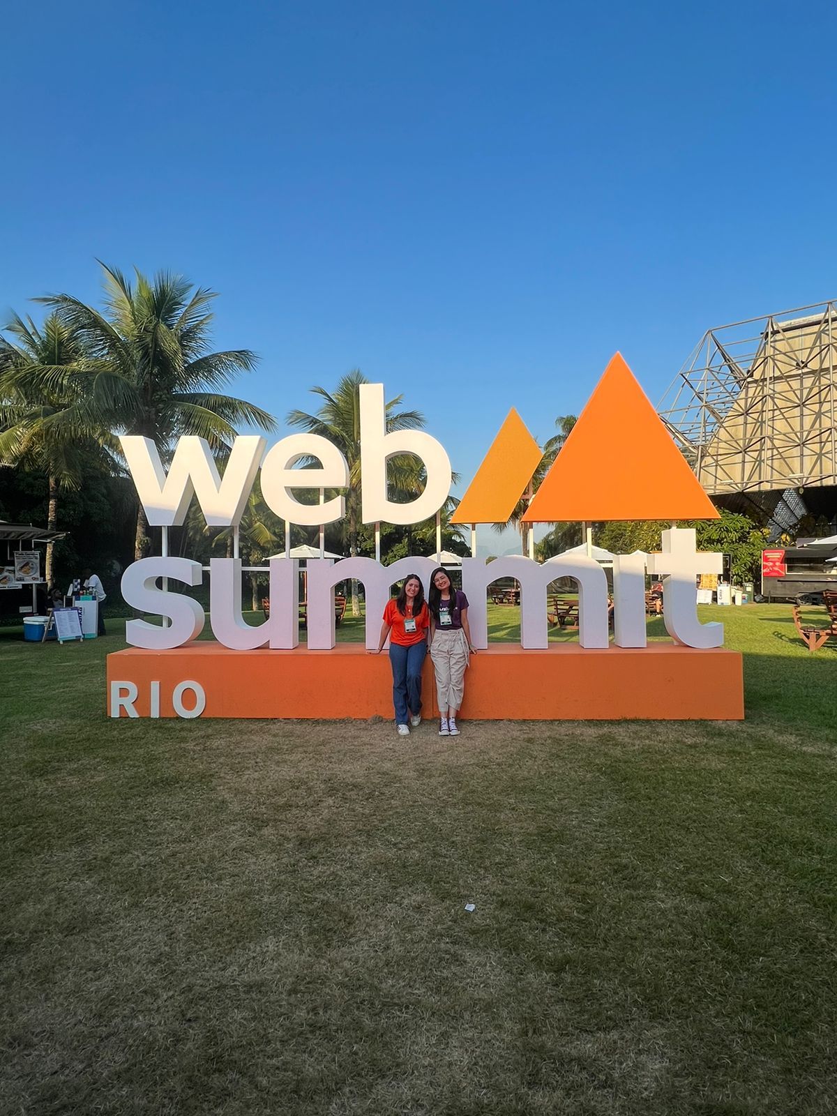 Placa do WebSummit com duas mulheres em pé na frente da placa